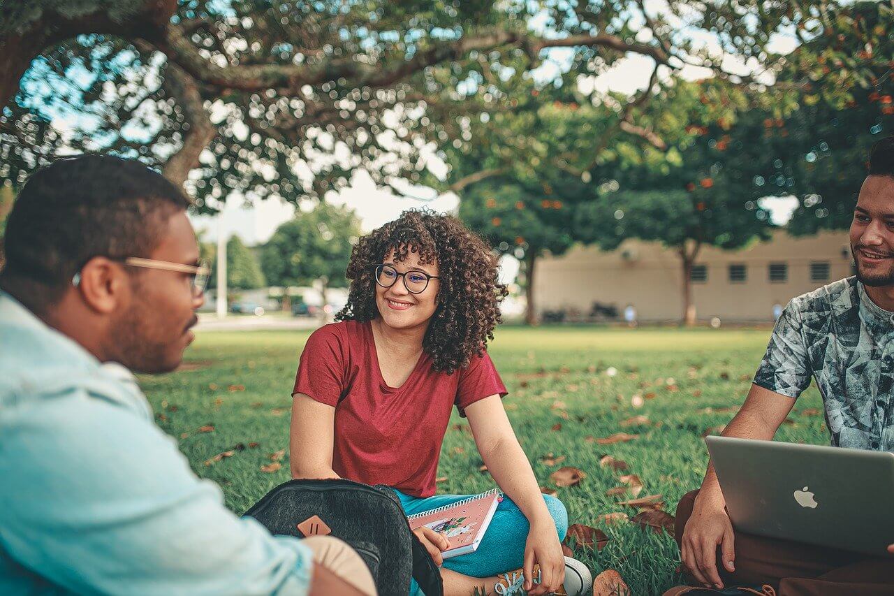 Three people sitting together outdoors in conversation